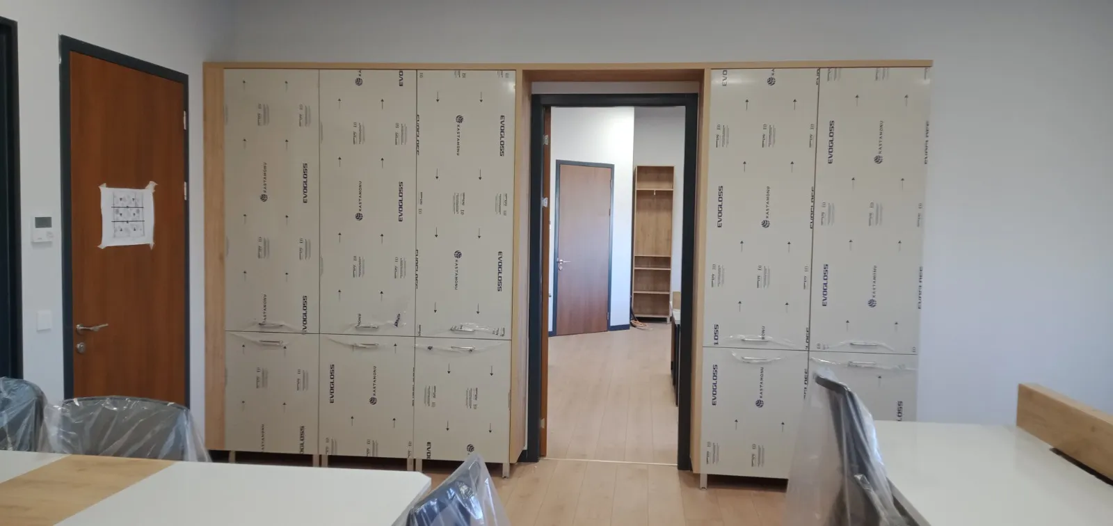 Ofis odasında kapı boşluğunu çevreleyen krem kapaklı tam boy dolap sırası