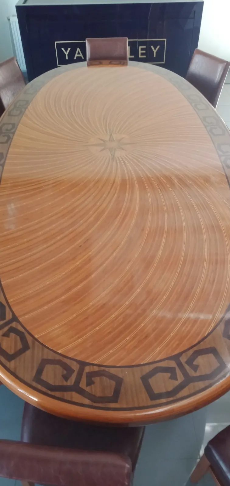 Yıldız kakma motifli, parlak cilalı oval ahşap masa ve deri döşemeli sandalyeler