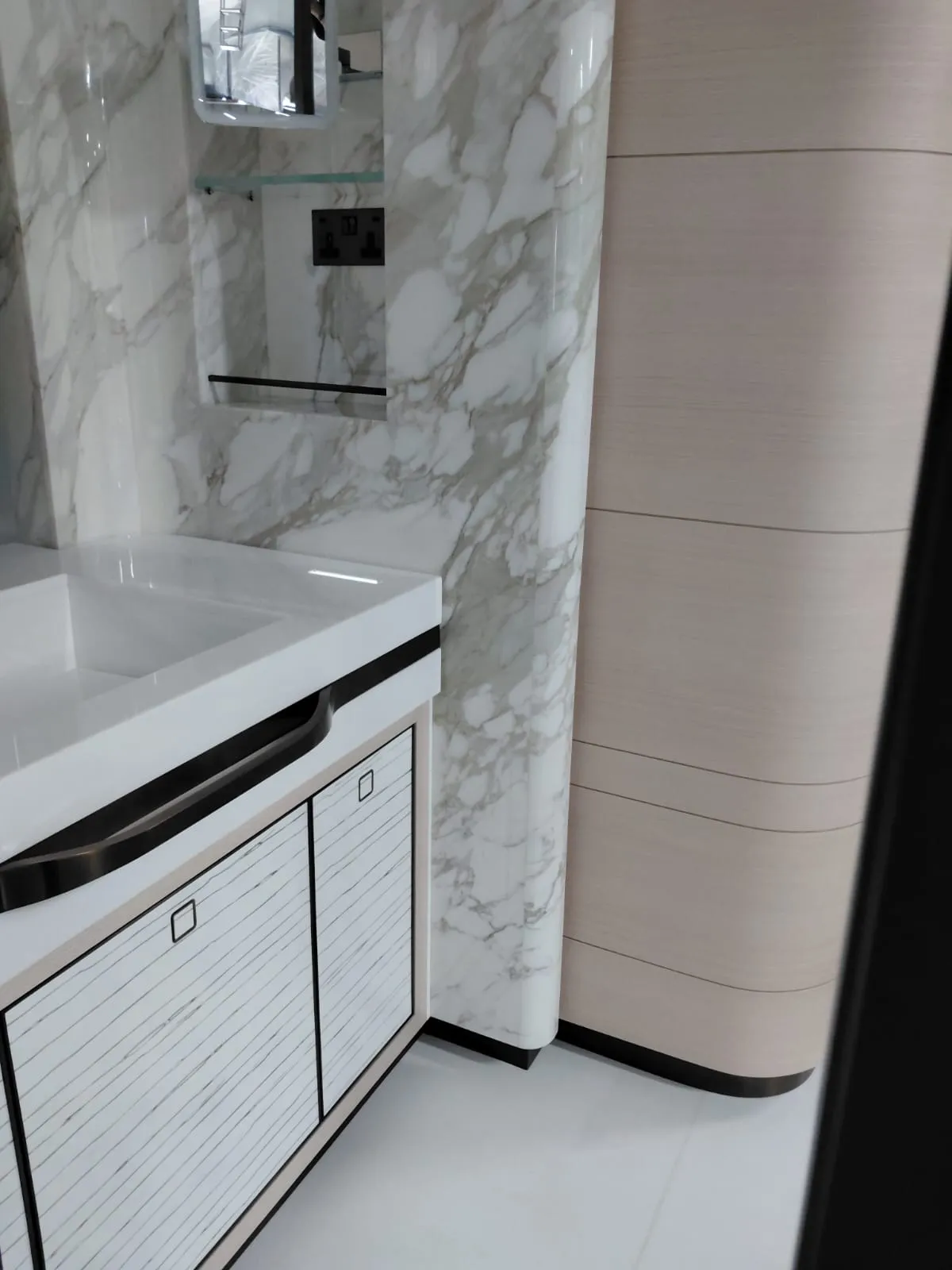 Damarlı parlak duvar kaplamalı banyoda beyaz tezgahlı lavabo dolabı ve çizgi desenli kapaklar
