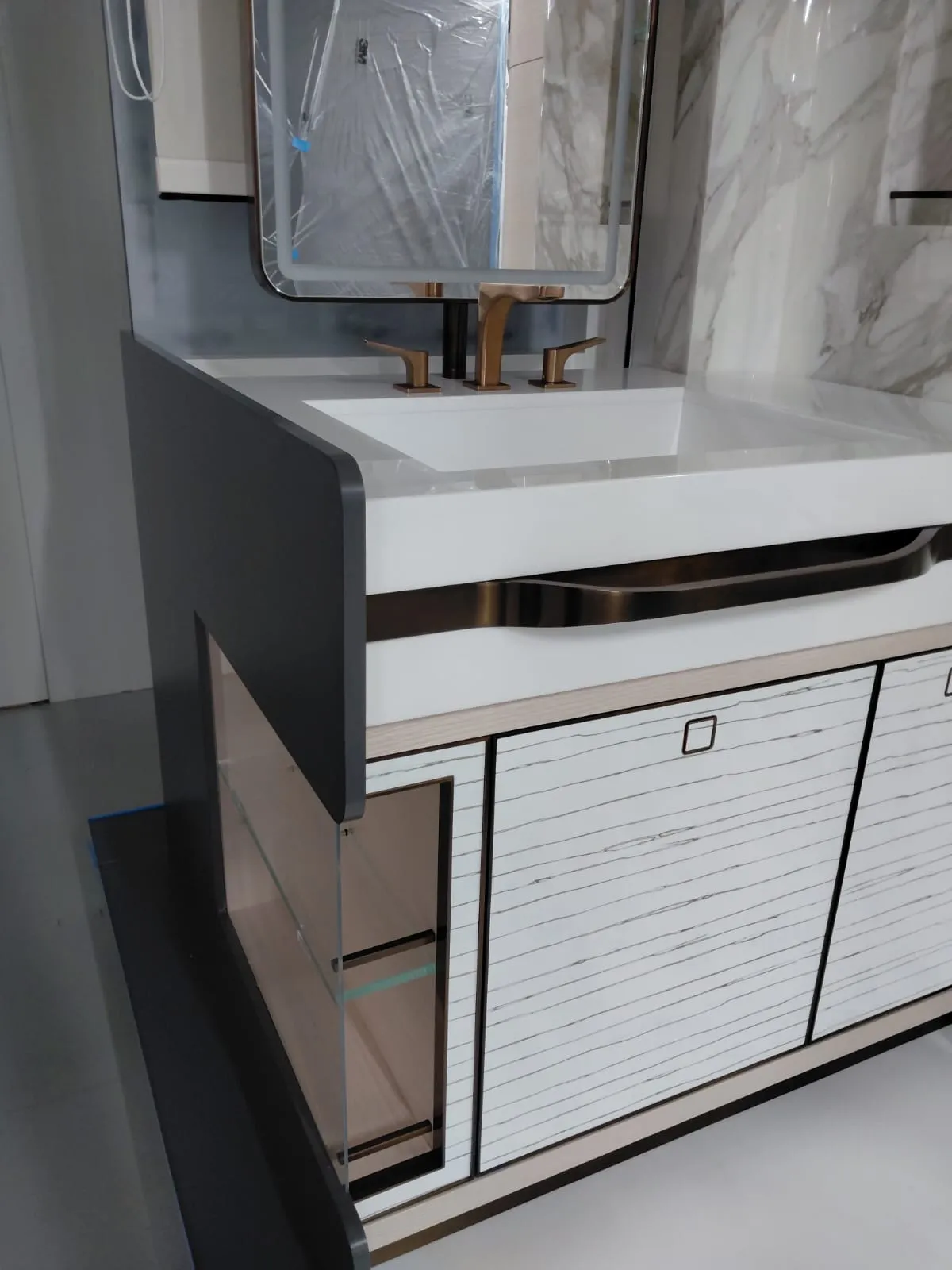 Beyaz damarlı kapaklı lavabo dolabı, bütünleşik tezgah ve bronz tonlu armatür
