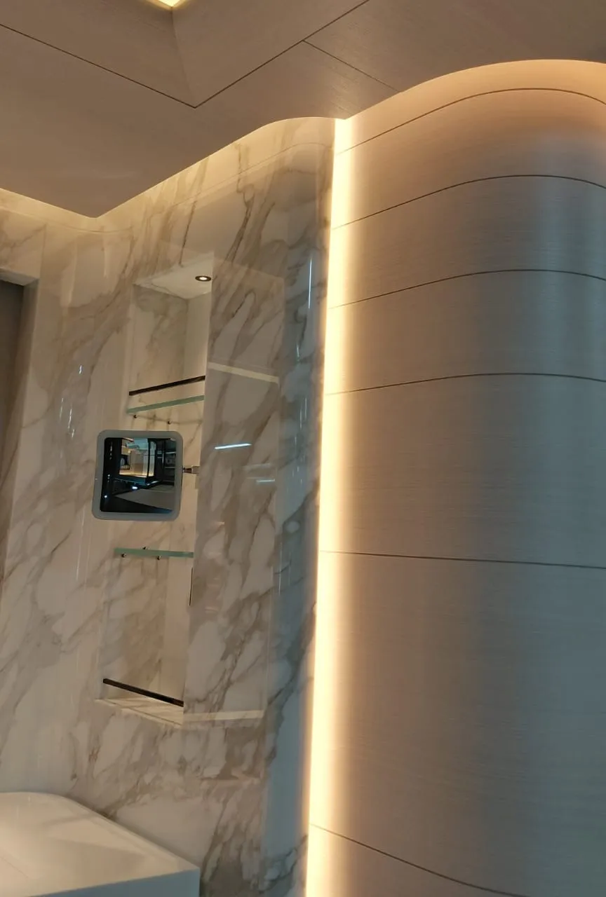 Işıklı aynalı lavabo ünitesi, mermer görünümlü duvar nişi ve cam raflar