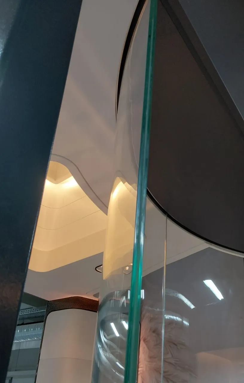 Kavisli cam bölme arkasında gizli aydınlatmalı krem kavisli tavan ünitesi
